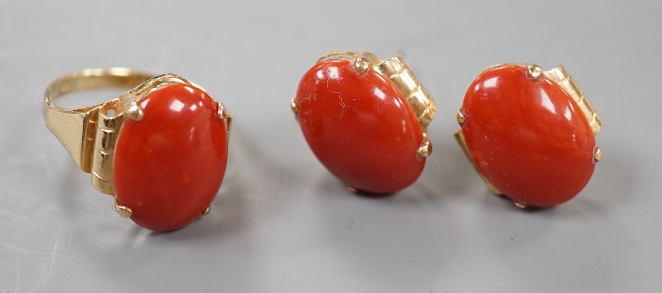 A 14k yellow metal and cabochon coral set oval ring, size N and a pair of matching earrings, lacking one butterfly, gross weight 11.5 grams.